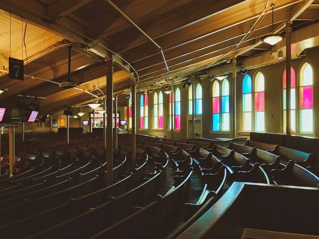 Curved wooden pews and stained-glass windows inside the Ryman Auditorium